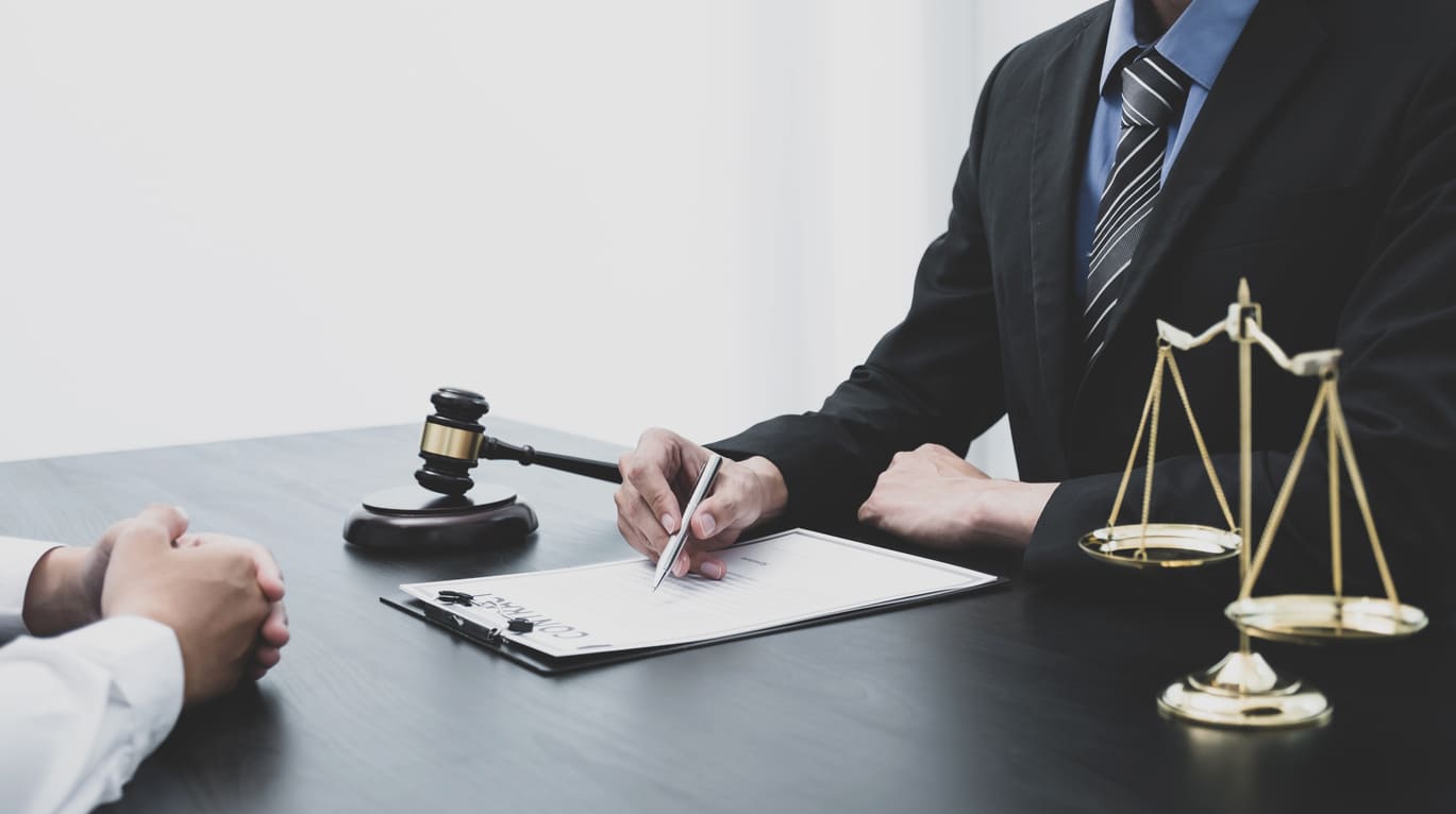 lawyer is explaining the terms of the legal contract document and asking the client to sign it properly.